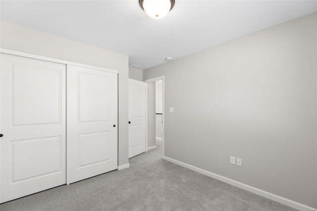 unfurnished bedroom featuring a closet and light colored carpet