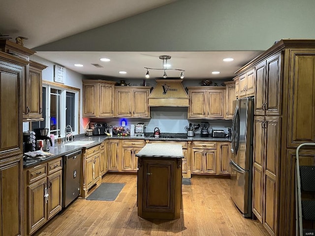 kitchen with a center island, lofted ceiling, sink, custom range hood, and stainless steel appliances