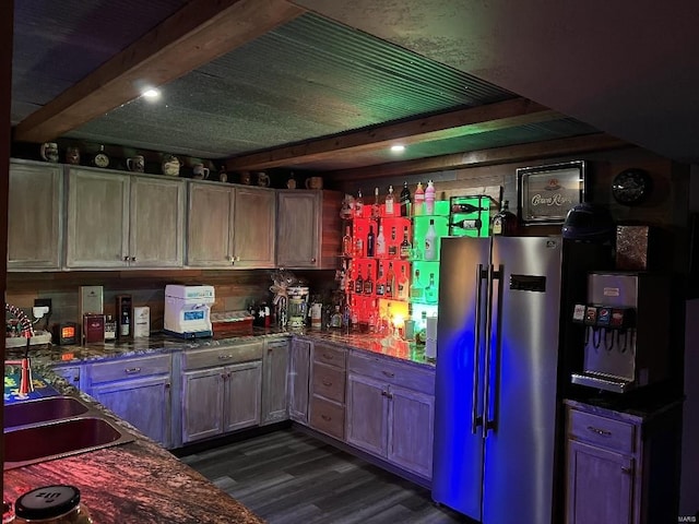 kitchen featuring stainless steel refrigerator, sink, beamed ceiling, dark hardwood / wood-style floors, and dark stone countertops