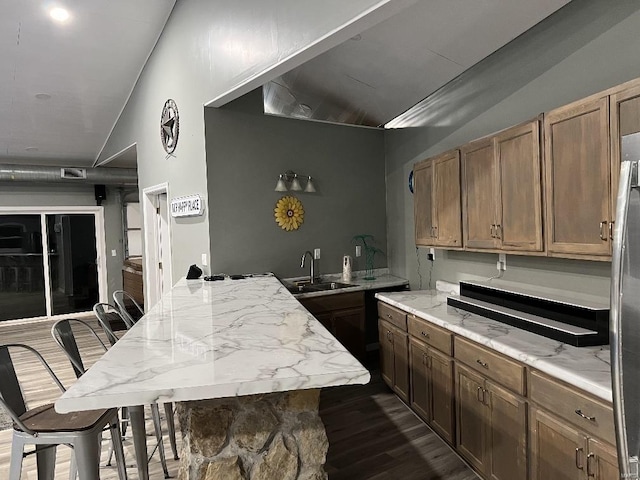 kitchen featuring dark hardwood / wood-style flooring, a kitchen island, a breakfast bar area, and sink