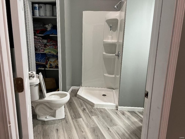 bathroom featuring hardwood / wood-style floors, toilet, and a shower