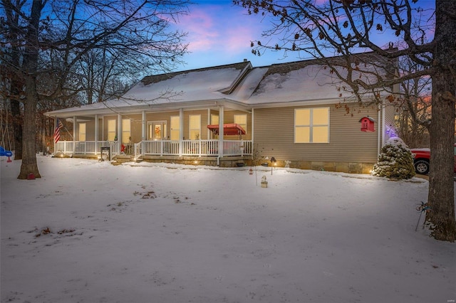 snow covered back of property with covered porch