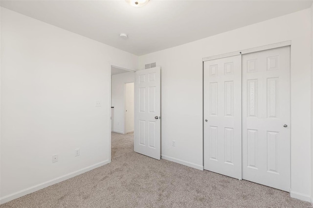 unfurnished bedroom featuring light colored carpet and a closet