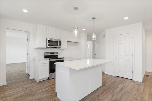 kitchen with white cabinetry, a center island, light hardwood / wood-style flooring, pendant lighting, and appliances with stainless steel finishes