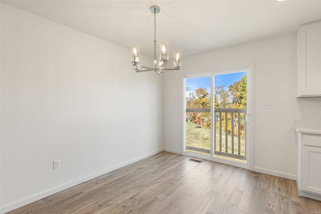 unfurnished dining area featuring light hardwood / wood-style floors and a notable chandelier