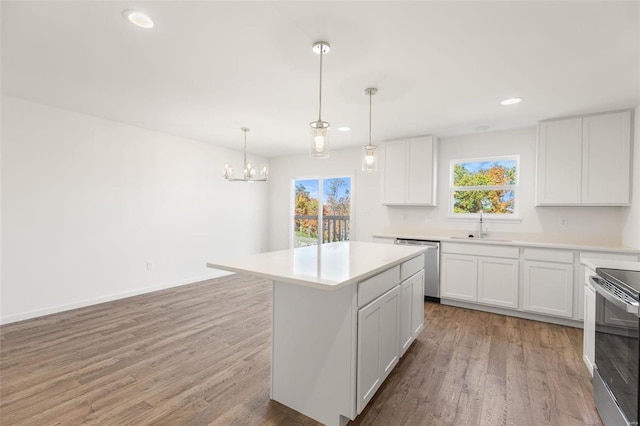 kitchen with a center island, white cabinets, sink, decorative light fixtures, and stainless steel appliances