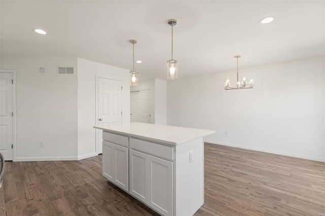 kitchen featuring wood-type flooring, a chandelier, a center island, white cabinetry, and hanging light fixtures