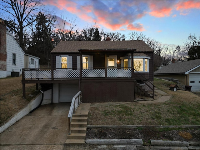 view of front facade featuring cooling unit, a porch, and a garage