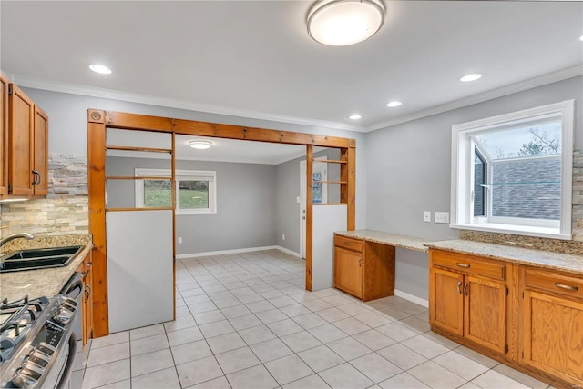 kitchen featuring light stone counters, ornamental molding, sink, and stainless steel range with gas stovetop