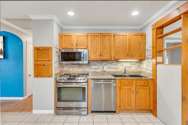 kitchen featuring appliances with stainless steel finishes, tasteful backsplash, ornamental molding, sink, and light tile patterned flooring