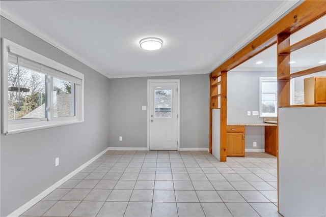 foyer with light tile patterned floors, ornamental molding, and a healthy amount of sunlight