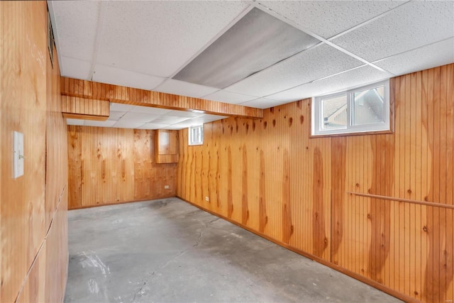 basement with a paneled ceiling and wooden walls