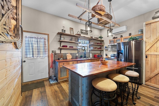 kitchen with wooden counters, a wall unit AC, pendant lighting, sink, and stainless steel appliances