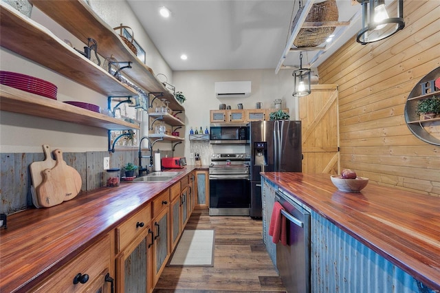 kitchen featuring pendant lighting, butcher block counters, stainless steel appliances, sink, and a wall mounted AC