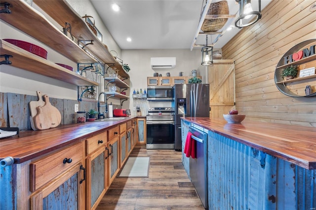 kitchen with butcher block countertops, sink, stainless steel appliances, and pendant lighting