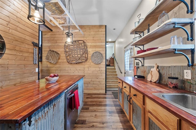 kitchen with butcher block counters, wood walls, decorative light fixtures, dark wood-type flooring, and dishwasher