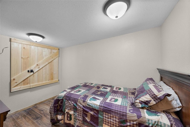 bedroom with a textured ceiling and dark hardwood / wood-style floors