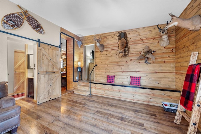 interior space with hardwood / wood-style floors, a barn door, and wood walls