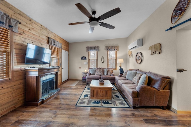 living room with ceiling fan, dark wood-type flooring, wood walls, and a wall unit AC