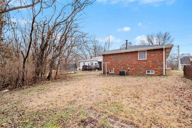 rear view of property featuring central AC unit and a trampoline