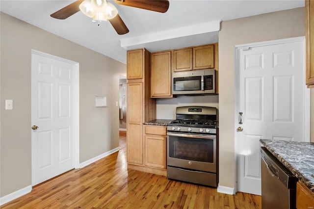 kitchen with dark stone counters, stainless steel appliances, and light wood-type flooring