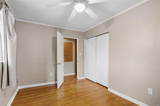 unfurnished bedroom featuring ceiling fan, light hardwood / wood-style floors, crown molding, and a closet