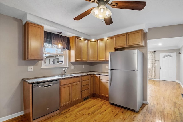 kitchen featuring appliances with stainless steel finishes, ceiling fan, sink, decorative light fixtures, and light hardwood / wood-style floors