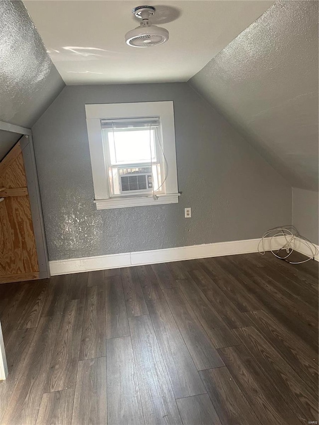 additional living space featuring dark wood-type flooring, a textured ceiling, and lofted ceiling