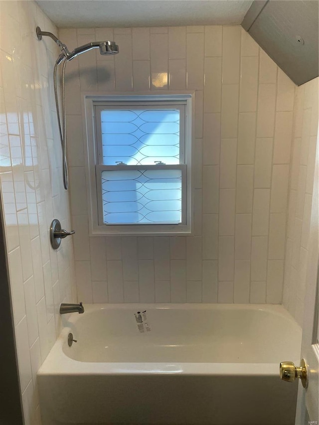 bathroom with vaulted ceiling and tiled shower / bath