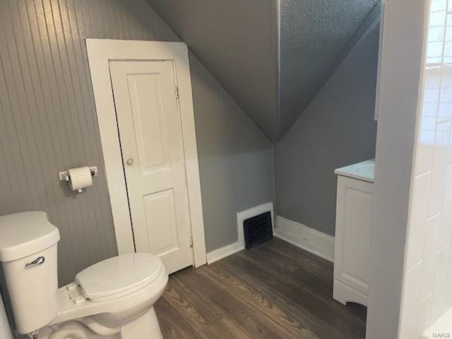 bathroom featuring wood-type flooring, toilet, vaulted ceiling, and vanity