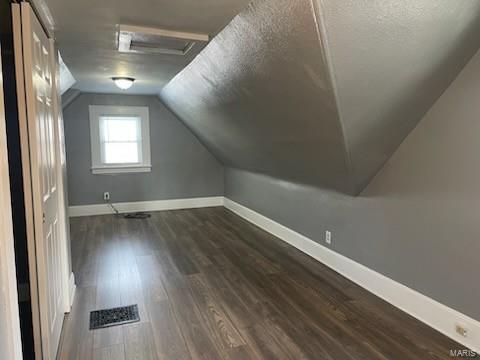 bonus room featuring vaulted ceiling, dark wood-type flooring, and a textured ceiling