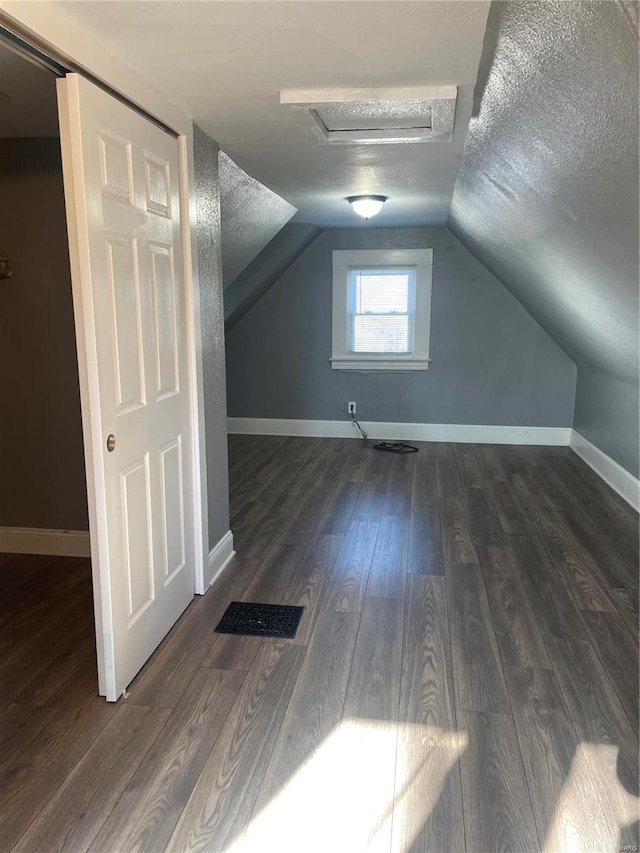 additional living space with a textured ceiling, dark hardwood / wood-style floors, and vaulted ceiling