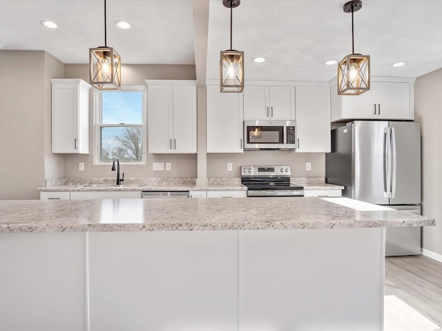 kitchen featuring light stone countertops, pendant lighting, stainless steel appliances, and white cabinetry