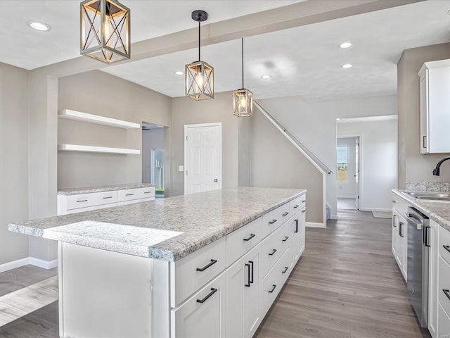 kitchen featuring white cabinets, dishwasher, a kitchen island, and pendant lighting