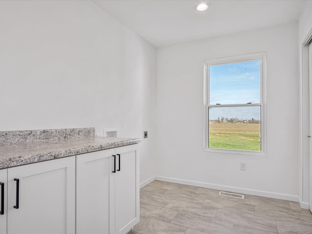 laundry room with washer hookup, electric dryer hookup, cabinets, and a wealth of natural light