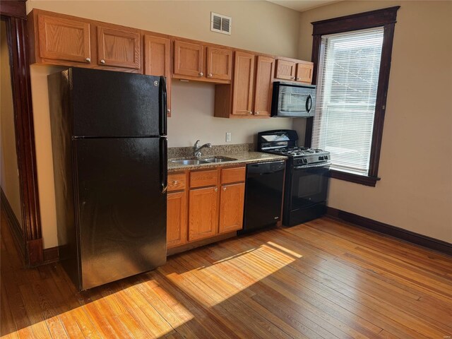 kitchen featuring black appliances, light hardwood / wood-style floors, sink, and a wealth of natural light