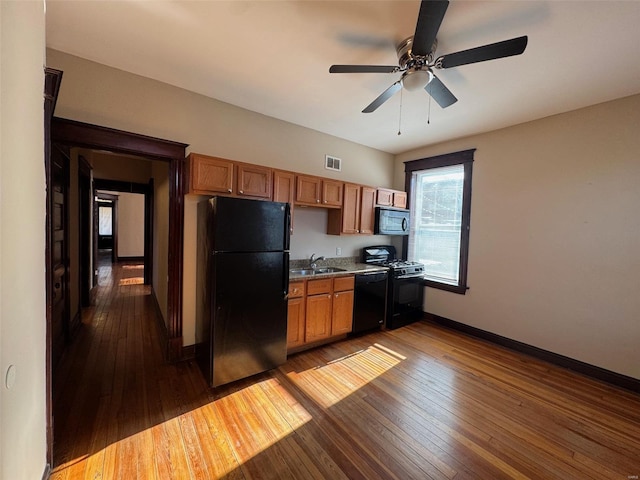 kitchen featuring ceiling fan, sink, black appliances, and dark hardwood / wood-style floors