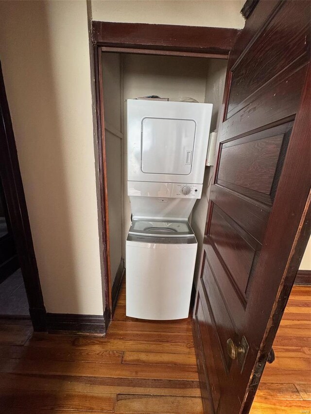 laundry room with hardwood / wood-style floors and stacked washing maching and dryer