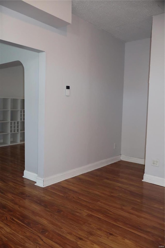 empty room featuring a textured ceiling and dark hardwood / wood-style flooring