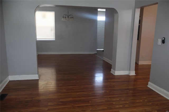 empty room with a chandelier and dark hardwood / wood-style flooring