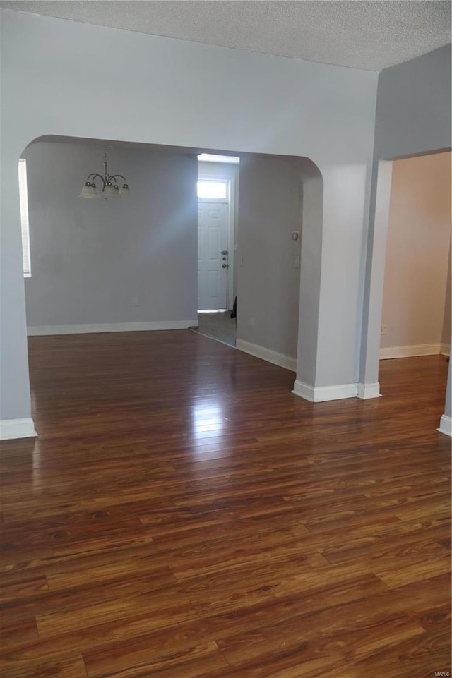 unfurnished room with dark wood-type flooring and a textured ceiling