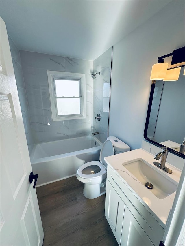 full bathroom featuring wood-type flooring, tiled shower / bath combo, vanity, and toilet