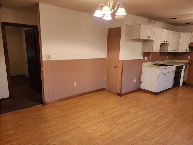 kitchen with white cabinetry, dishwasher, hanging light fixtures, a notable chandelier, and light hardwood / wood-style floors