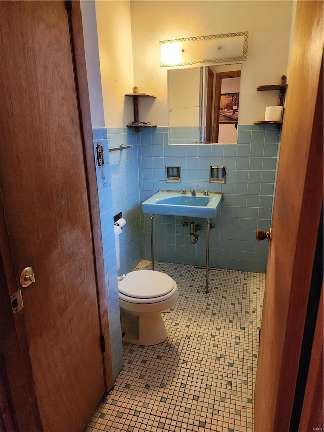 bathroom featuring toilet, tile patterned floors, and tile walls