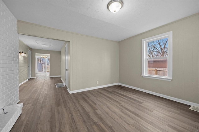 empty room with a wealth of natural light, hardwood / wood-style floors, and a textured ceiling