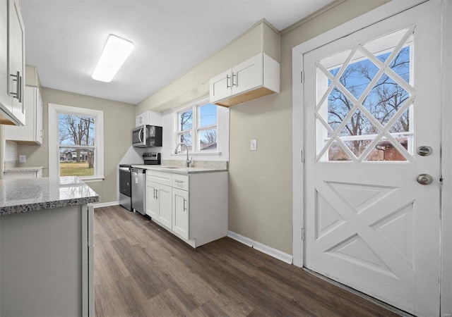 kitchen featuring light stone counters, white cabinetry, stainless steel appliances, and a wealth of natural light