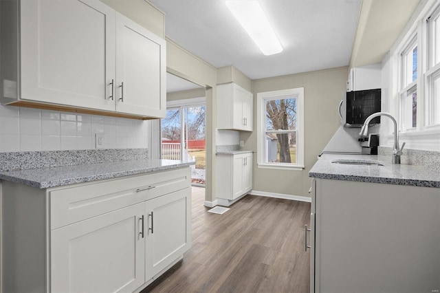 kitchen featuring white cabinets, decorative backsplash, and light stone counters