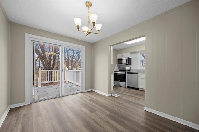 unfurnished dining area with ornamental molding, a textured ceiling, hardwood / wood-style flooring, and a notable chandelier