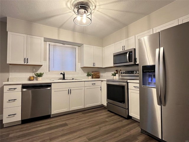 kitchen with dark hardwood / wood-style flooring, tasteful backsplash, stainless steel appliances, sink, and white cabinetry