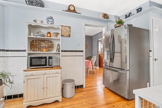 kitchen featuring light hardwood / wood-style flooring, stainless steel appliances, and tile walls